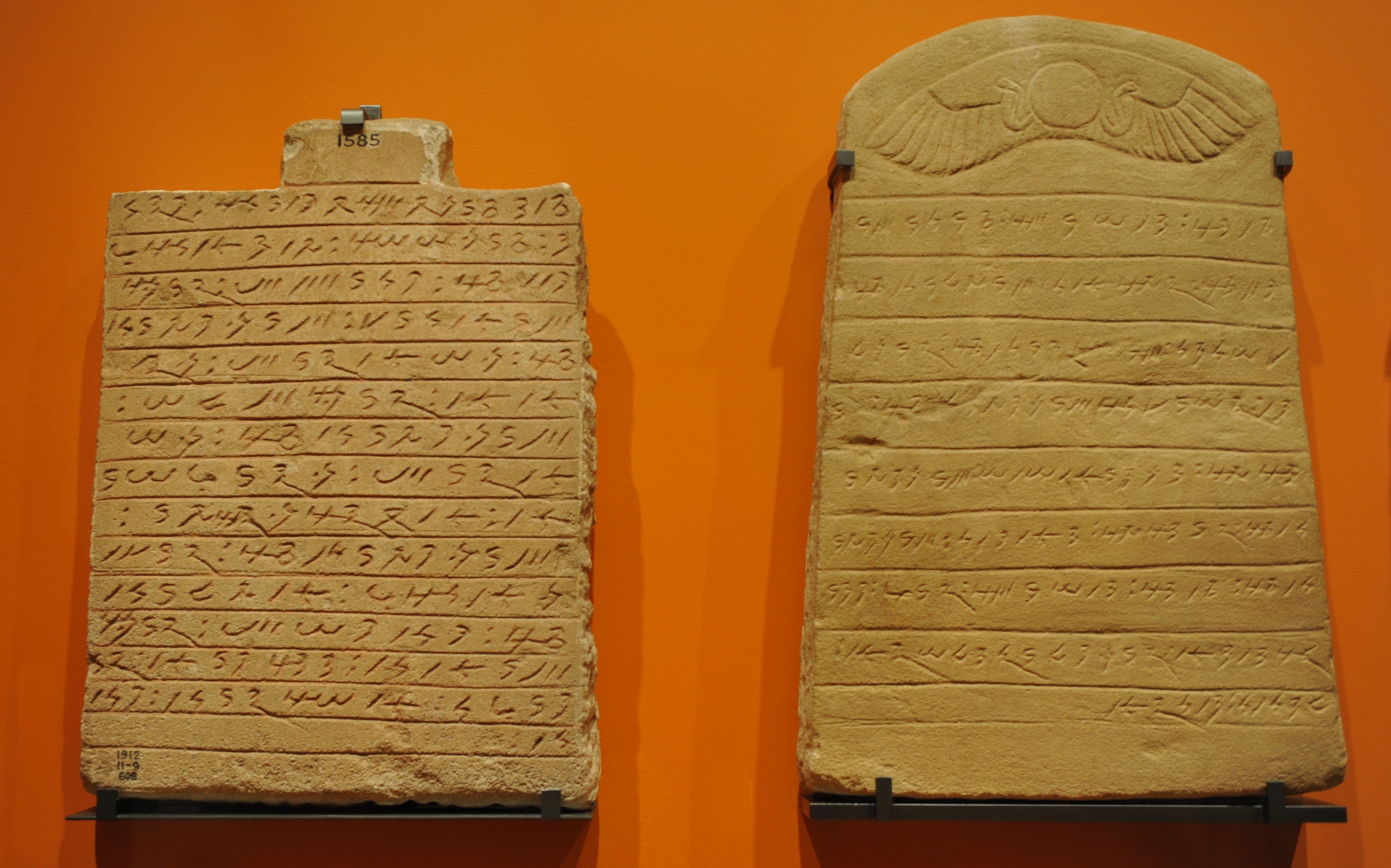 Two ancient Meroitic cursive inscriptions carved into stone tablets, displayed side by side in a museum
