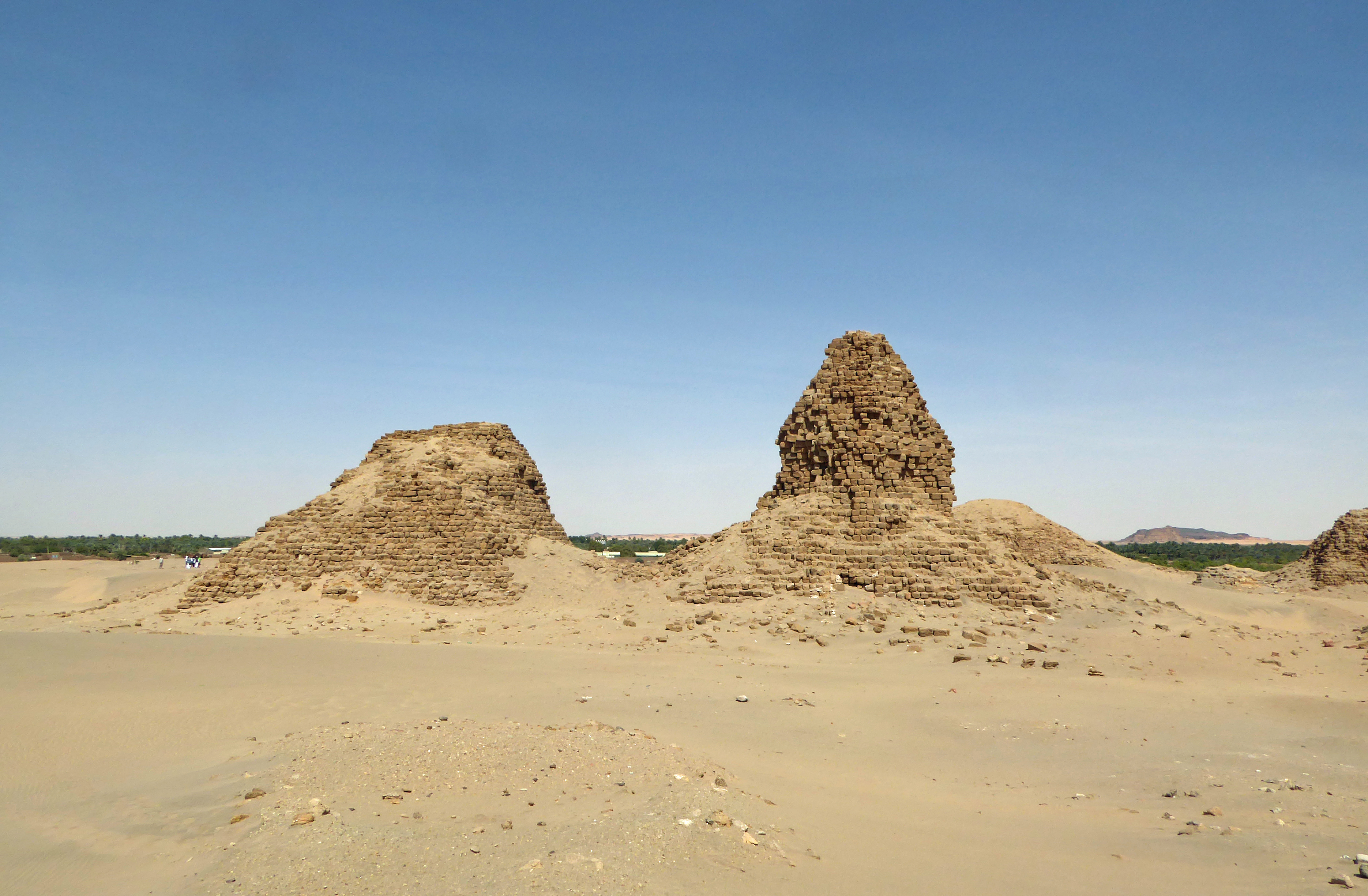 Row of steep stone pyramids at the royal cemetery of Nuri in Sudan, seen from the desert ground